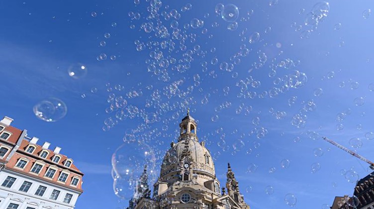 Seifenblasen fliegen vor der Dresdner Frauenkirche durch die Luft. Foto: Robert Michael/dpa-Zentralbild/dpa/Archivbild