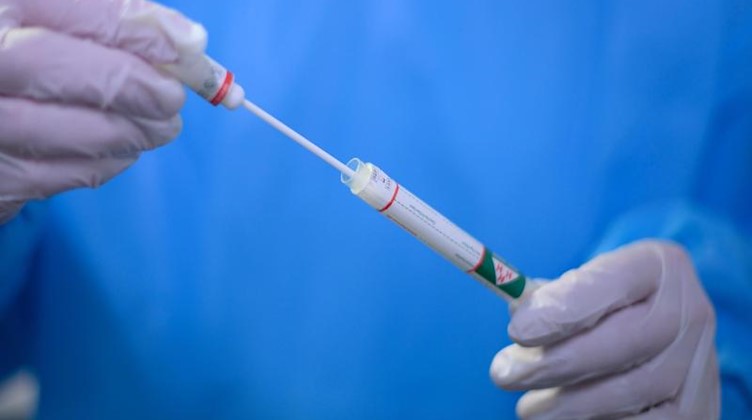 Ein Arzt hält einen Coronavirus-Test in den Händen. Foto: Robert Michael/dpa-Zentralbild/dpa/Symbolbild
