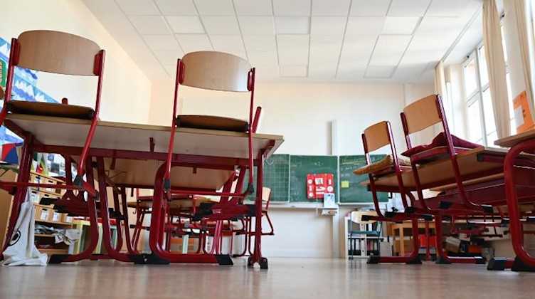 Stühle sind in einem leeren Klassenzimmer auf den Tischen abgestellt. Foto: Arne Dedert/dpa/Symbolbild