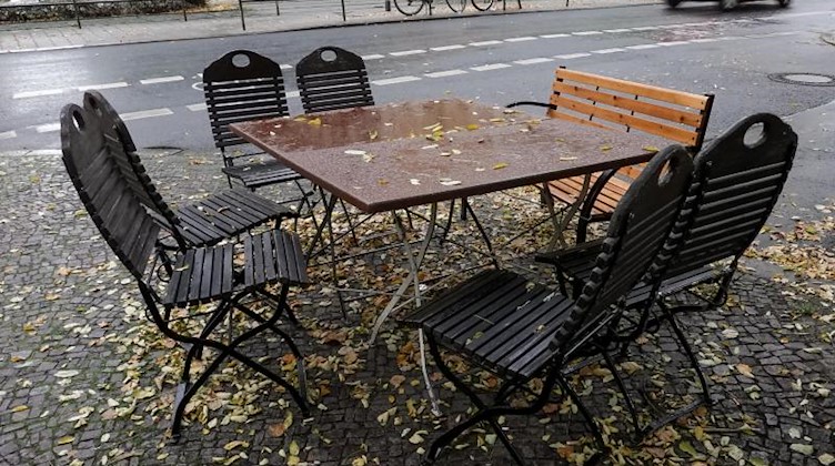 Nasses Laub bedeckt Stühle und Tische auf einem geschlossenen Freisitz. Foto: Jan Woitas/dpa-Zentralbild/dpa/Archivbild