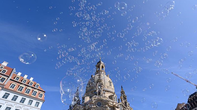 Seifenblasen fliegen vor der Frauenkirche durch die Luft. Foto: Robert Michael/dpa-Zentralbild/dpa/Archivbild