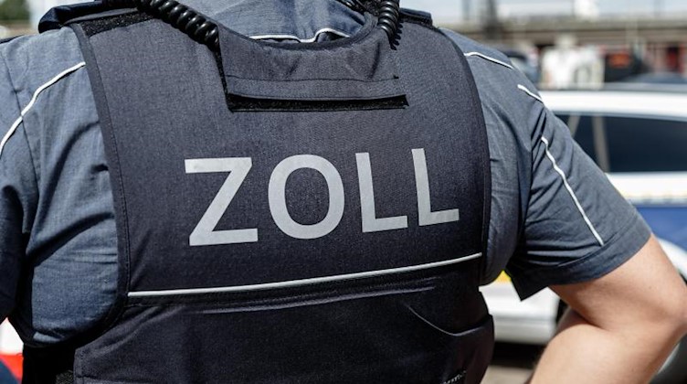 Ein Beamter trägt während seines Dienstes eine Schutzweste mit der Rückenaufschrift «Zoll». Foto: Markus Scholz/dpa/Symbolbild