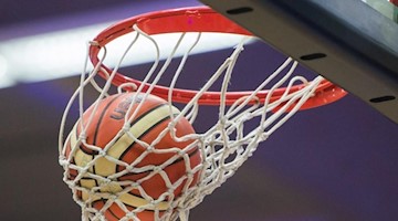 Ein Basketball fällt in den Basketballkorb. Foto: picture alliance / dpa/Symbolbild