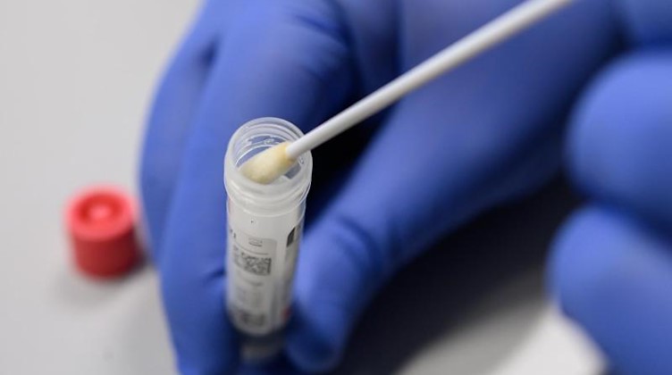 Ein Mann zeigt einen Abstrich für das Testverfahren auf das Virus SARS-CoV-2. Foto: Sebastian Gollnow/dpa/Symbolbild