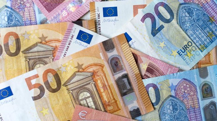 Zahlreiche Banknoten zu 10, 20 und 50 Euro liegen auf einem Tisch. Foto: Monika Skolimowska/zb/dpa/Symbolbild