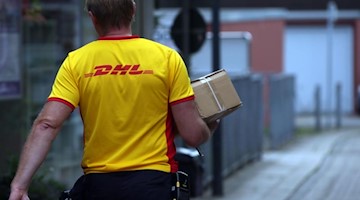 Ein Paketzustellender von Deutsche Post DHL liefert ein Paket aus. Foto: picture alliance / dpa/Symbolbild