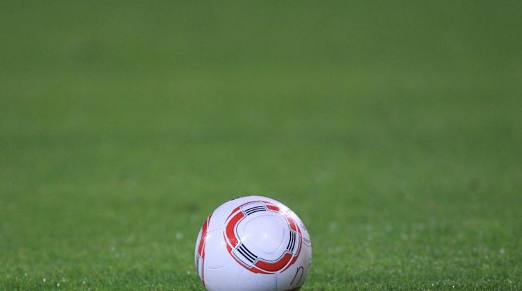 Ein Fussball liegt auf dem Rasen. Foto: picture alliance / dpa / Archivbild