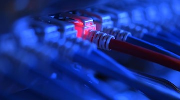 Ein Netzwerkkabelstecker leuchtet in einer Netzwerkzentrale rot. Foto: Felix Kästle/dpa/Symbolbild