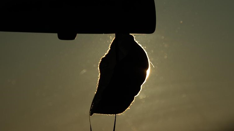 Ein Mund-Nasen-Schutz hängt in einem Auto am Rückspiegel. Foto: Sebastian Gollnow/dpa/Symbolbild