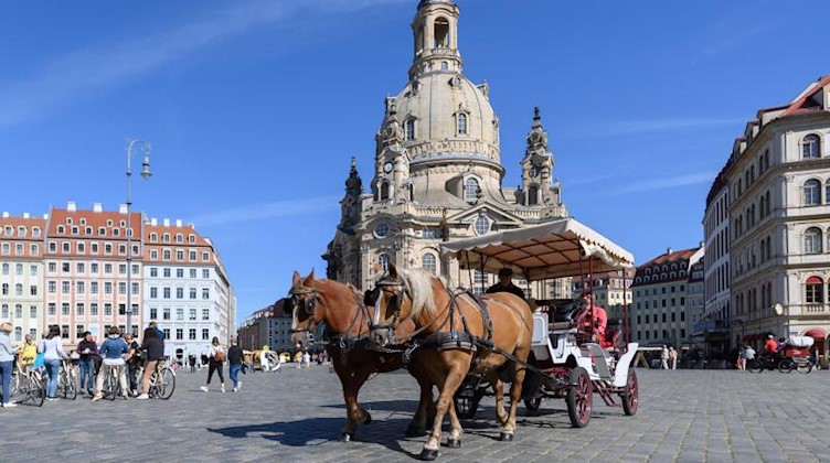 Eine Pferdekutsche mit Touristen fährt über den Neumarkt vor der Frauenkirche. Foto: Robert Michael/dpa-Zentralbild/dpa/Symbolbild