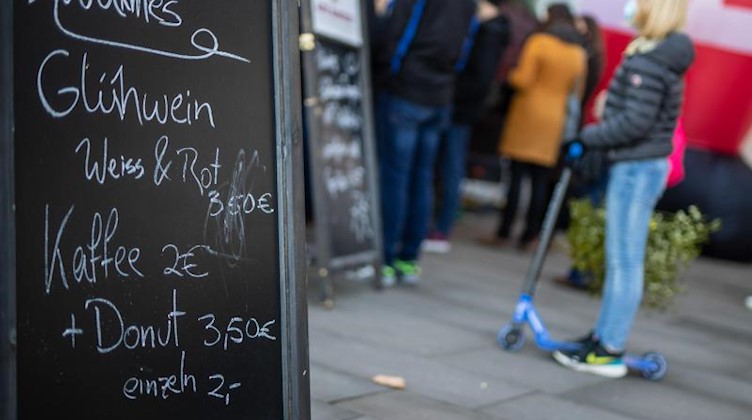 Menschen stehen an einem Glühwein-Stand. Foto: Christoph Schmidt/dpa
