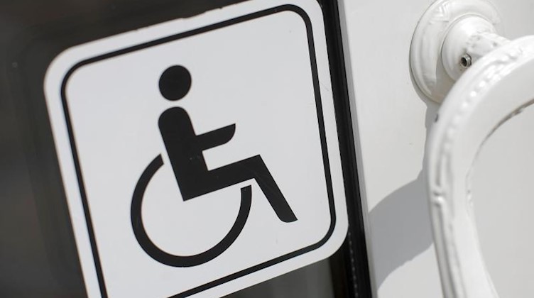 Ein Schild für Menschen mit Behinderung klebt an einer Tür. Foto: picture alliance / dpa/Symbolbild