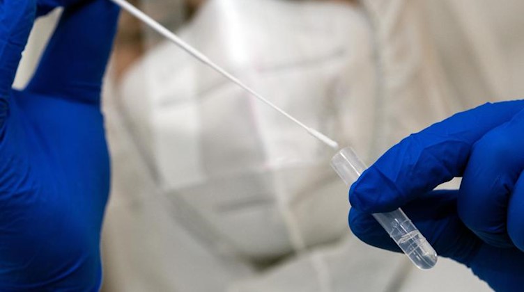 Ein Mitarbeiter eines Covid-19-Schnelltest-Zentrums bearbeitet eine Probe für einen Schnelltest. Foto: Federico Gambarini/dpa