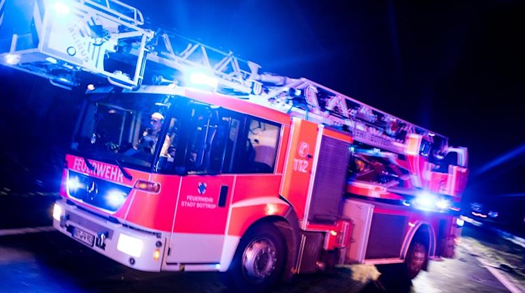 Ein Drehleiterwagen der Feuerwehr fährt mit Blaulicht an einer Unfallstelle vorbei. Foto: Marcel Kusch/dpa/Illustration