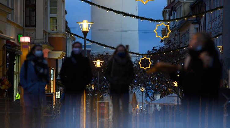 Passanten mit Mund-Nasen-Schutz gehen durch eine festlich dekorierte Fußgängerzone in Bautzen. Foto: Robert Michael/dpa-Zentralbild/dpa/Symbolbild