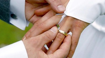 Einer Braut wird ein Ehering angesteckt. Foto: Andreas Lander/dpa-Zentralbild/dpa