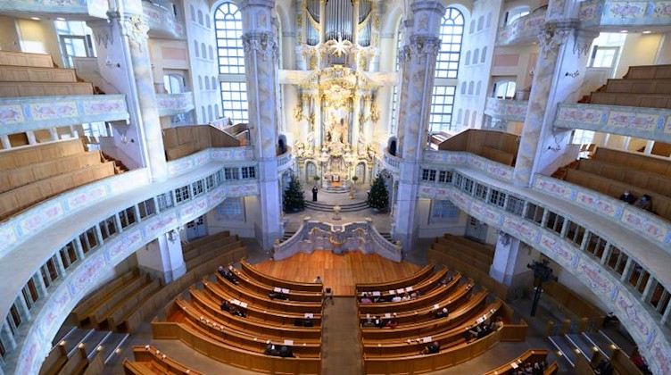 Besucher sitzen an Heilig Abend in der Frauenkirche in Dresden. Foto: Sebastian Kahnert/dpa-Zentralbild/dpa