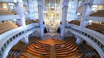 Besucher sitzen an Heilig Abend in der Frauenkirche in Dresden. Foto: Sebastian Kahnert/dpa-Zentralbild/dpa