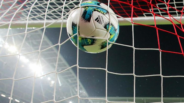 Ein Fußball fliegt ins Netz. Foto: Jan Woitas/zb/dpa/Symbolbild