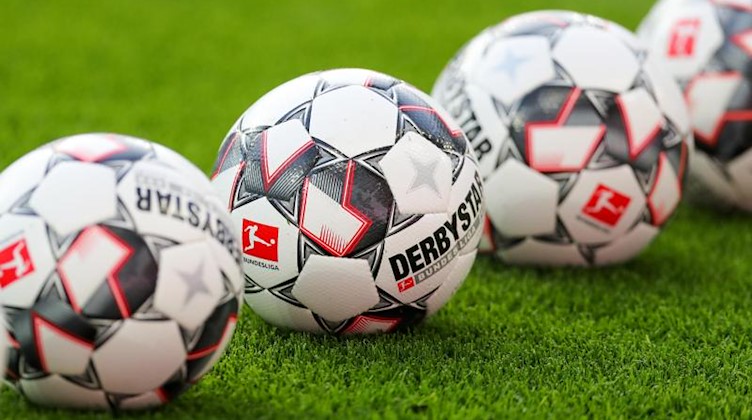 Eine Reihe von Fußbällen auf dem Rasen. Foto: Jan Woitas/zb/dpa/Symbolbild