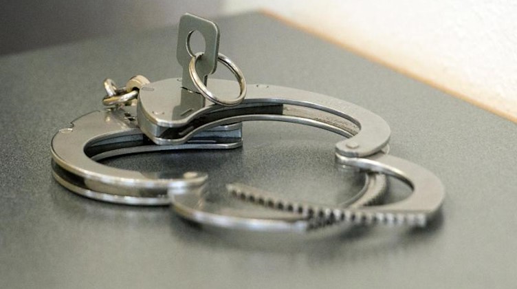 Handschellen liegen auf einem Tisch. Foto: Armin Weigel/dpa/Symbolbild