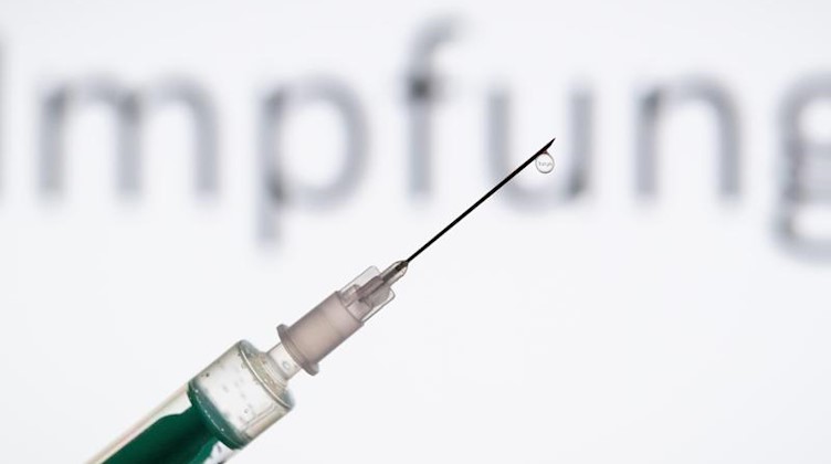 Eine Spritze wird vor einen Schriftzug «Impfung» gehalten. Foto: Friso Gentsch/dpa/Illustration