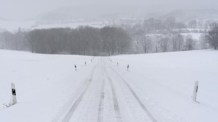 Eine Fahrspur zieht sich durch eine verschneite Straße im Erzgebirge. Foto: Robert Michael/dpa-Zentralbild/dpa