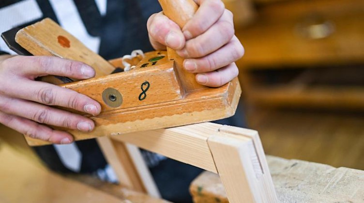 Ein Auszubildender im Schreiner-Handwerk arbeitet mit dem Hobel an seinem Werkstück. Foto: Felix Kästle/dpa/Symbolbild