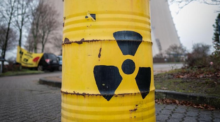 Eine gelbe Tonne mit dem Atom-Logo steht vor einem AKW. Foto: Peter Steffen/dpa/Symbolbild
