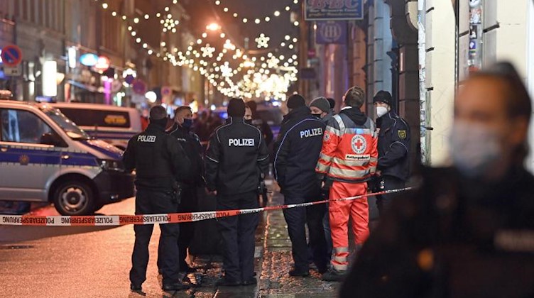 Polizisten und ein Mitarbeiter eines Rettungsdienstes hinter einer Polizeiabsperrung. Foto: Robert Michael/dpa-Zentralbild/dpa