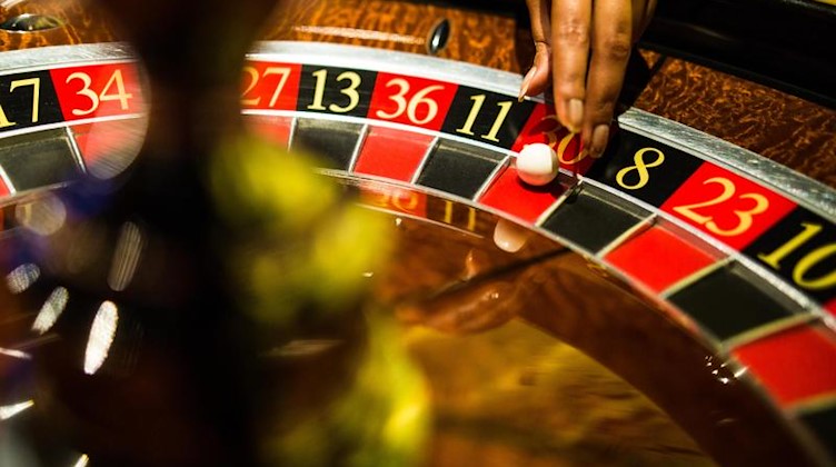 Eine Casinomitarbeiterin greift beim Spiel Roulette nach einer Kugel. Foto: Christoph Schmidt/dpa/Symbolbild