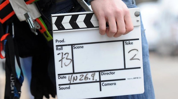 Ein Mitarbeiter eines Filmteams hält eine Filmklappe. Foto: Tobias Hase/dpa/Symbolbild