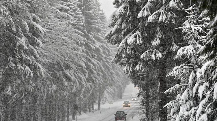 Autos fahren über eine verschneite Straße. Foto: Hendrik Schmidt/dpa-Zentralbild/ZB/Archivbild