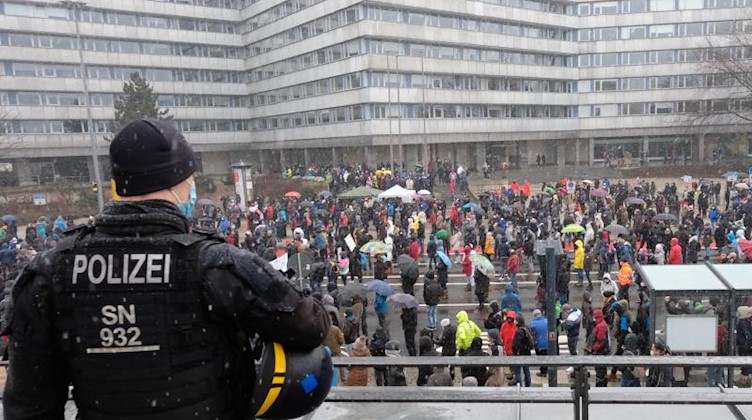 Ein Polizist beobachtet Teilnehmer einer Demonstration im Stadtzentrum. Foto: Sebastian Willnow/dpa-Zentralbild/dpa