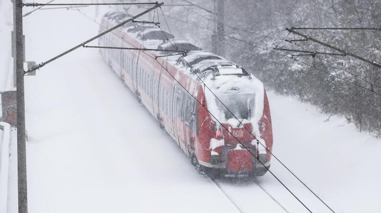Ein Regionalexpress fährt über verschneite Gleise. Foto: Jan Woitas/dpa-Zentralbild/dpa