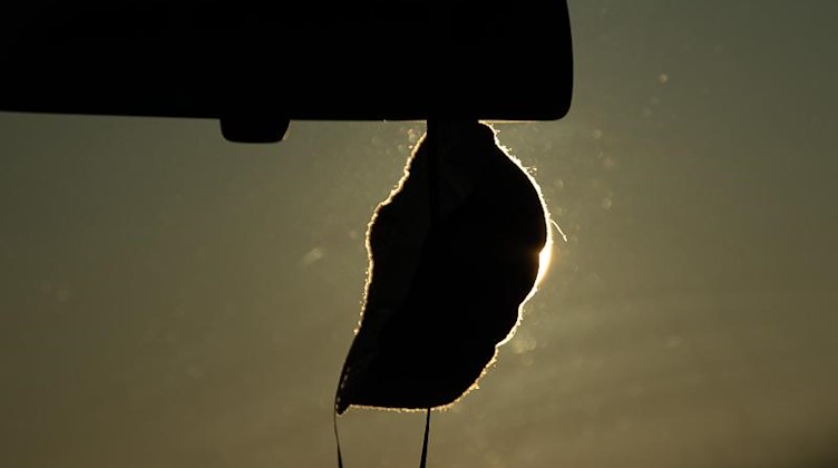 Eine FFP2-Maske hängt in einem Auto. Foto: Sebastian Gollnow/dpa/Symbolbild