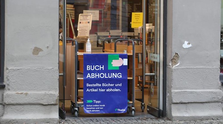 «Buchabholung» steht auf einer Tafel an einem Buchladen. Foto: Bodo Schackow/dpa-Zentralbild/dpa