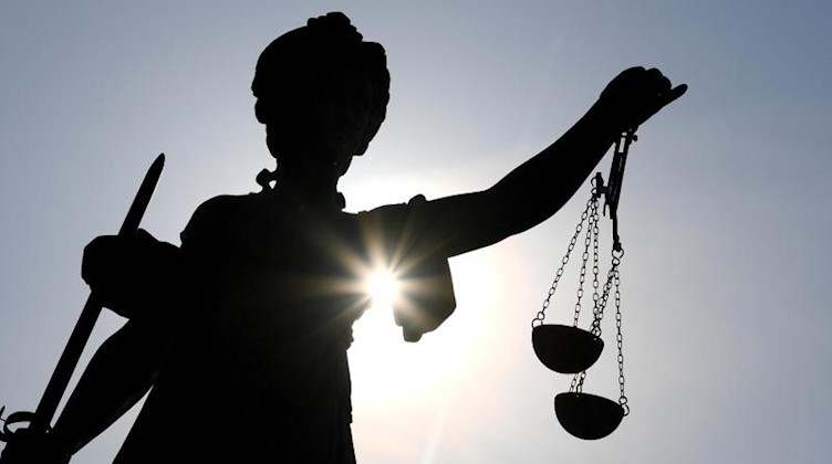 Die Statue der Justitia steht im Gegenlicht der Sonne. Foto: Arne Dedert/dpa/Symbolbild