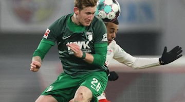 André Hahn (l) vom FC Augsburg und Leipzigs Tyler Adams kämpfen um den Ball. Foto: Jan Woitas/dpa-Zentralbild/dpa