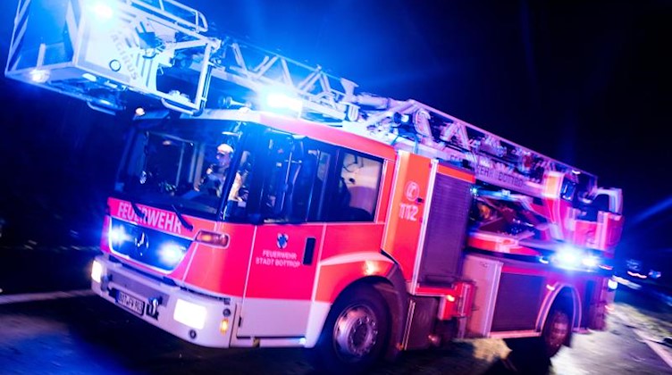 Ein Drehleiterwagen der Feuerwehr fährt mit Blaulicht an einer Unfallstelle vorbei. Foto: Marcel Kusch/dpa/Illustration