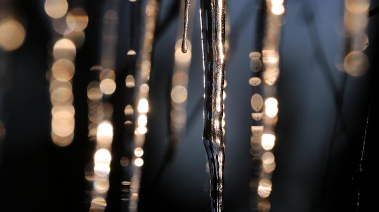 Von der Dachrinne eines Hauses hängende Eiszapfen glitzern im Licht. Foto: Karl-Josef Hildenbrand/dpa/Archivbild
