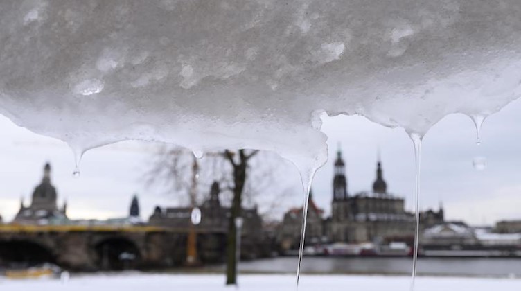 Schmelzender Schnee hängt am Ufer der Elbe vor der Kulisse der Dresdner Altstadt an einer Plane. Foto: Sebastian Kahnert/dpa-Zentralbild/dpa/Archivbild