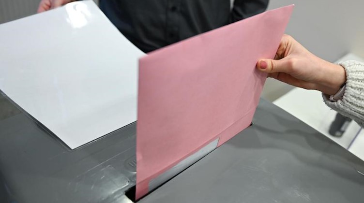 Ein Umschlag mit Briefwahlunterlagen wird in eine Wahlurne geworfen. Foto: Arne Dedert/dpa/Symbolbild