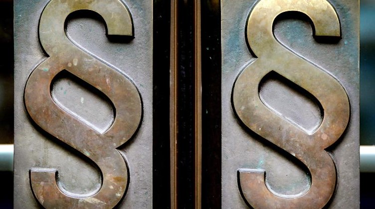 Paragrafen-Symbole sind an Türgriffen am Eingang zu einem Gericht zu sehen. Foto: Oliver Berg/dpa/Illustration
