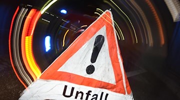 Ein Warndreieck mit dem Schriftzug «Unfall» steht vor einem Blaulicht auf der Straße. Foto: Patrick Seeger/dpa/Illustration