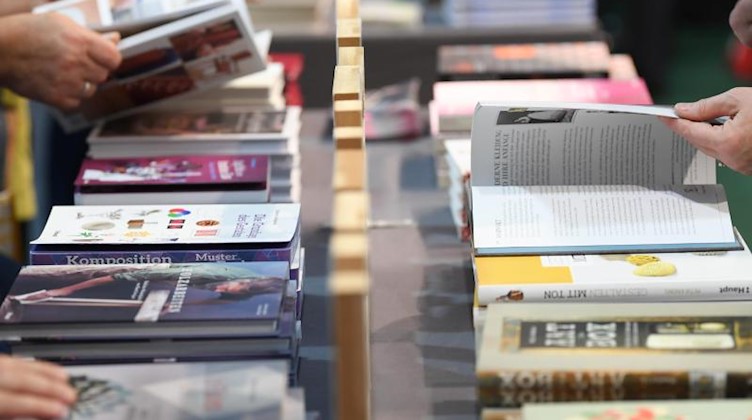 Besucher der Frankfurter Buchmesse blättern an einem Verlagsstand in Büchern. Foto: Arne Dedert/dpa/Symbolbild