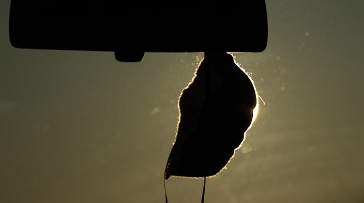 Eine Maske hängt in einem Auto. Foto: Sebastian Gollnow/dpa/Symbolbild