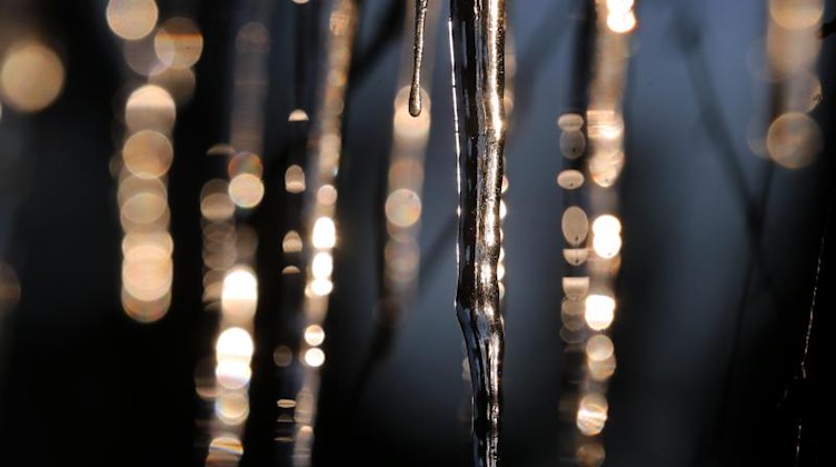 Von der Dachrinne eines Hauses hängende Eiszapfen glitzern im Sonnenlicht. Foto: Karl-Josef Hildenbrand/dpa/Archivbild
