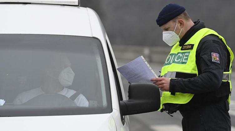 Ein Polizist überprüft während einer Straßenkontrolle die Papiere eines Autofahrers. Foto: Ondøej Deml/CTK/dpa