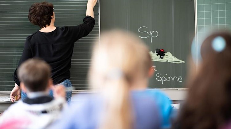 Eine Lehrerin schreibt in einer Grundschule Wörter an eine Tafel. Foto: Sebastian Gollnow/dpa/Symbolbild